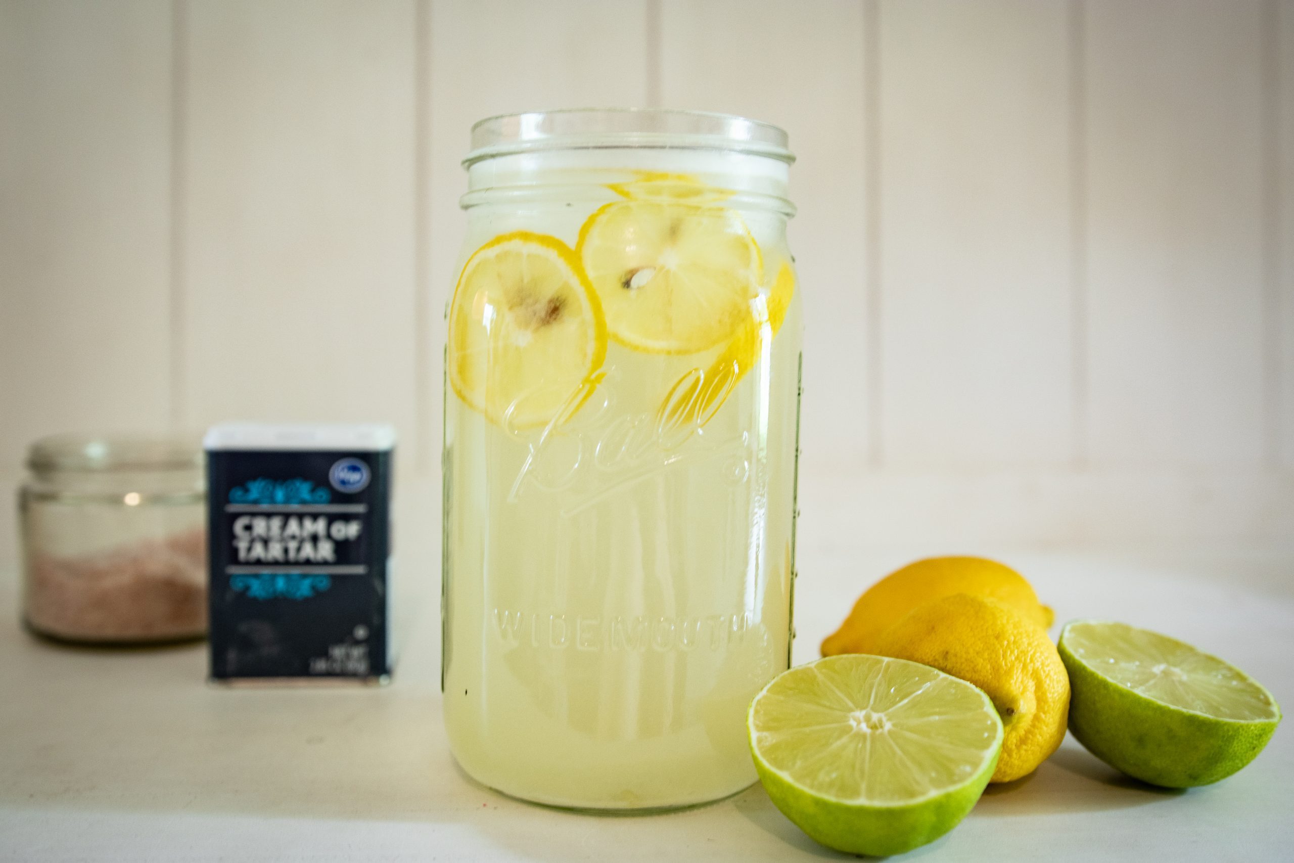 lemon lime electrolyte drink with lemons and limes next to it