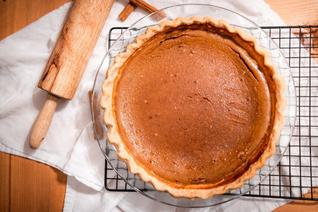 homemade pumpkin pie in pie plate with rolling pin