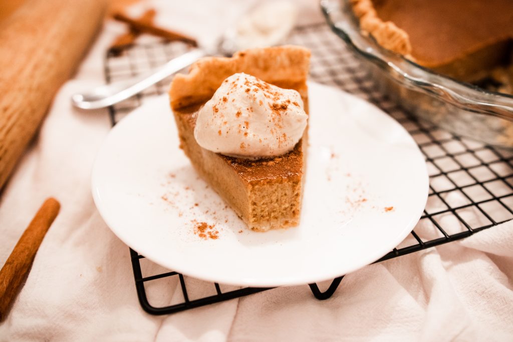 piece of homemade pumpkin pie on a plate with homemade whipped cream