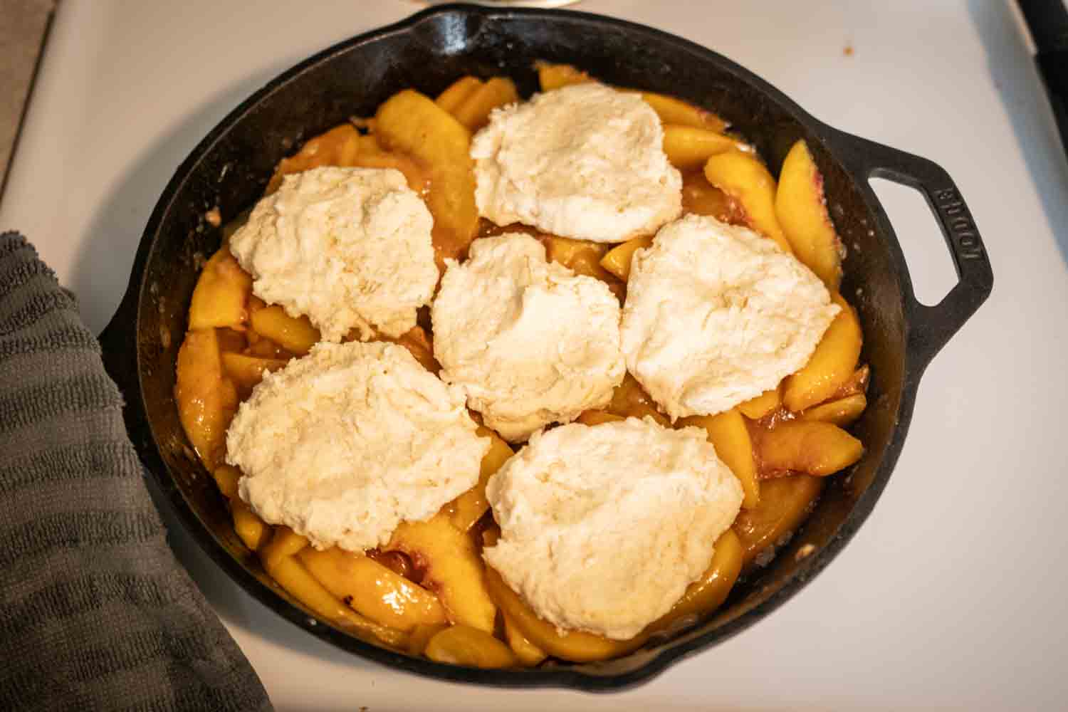peach filling with unbaked sourdough biscuits on top