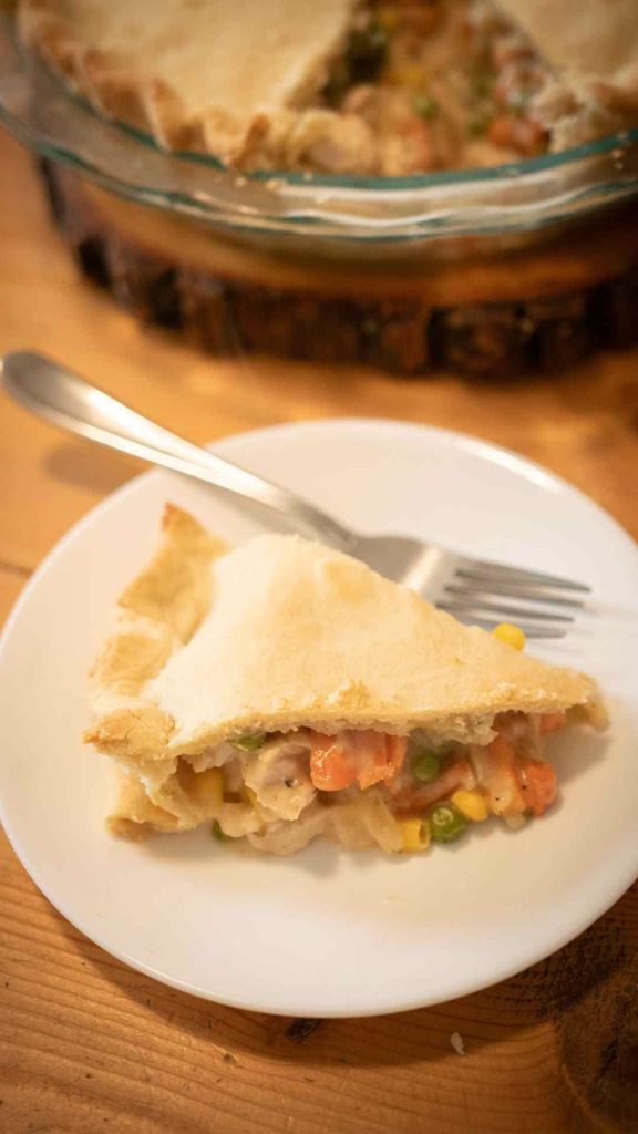 piece of sourdough chicken pot pie on a white plate with a fork