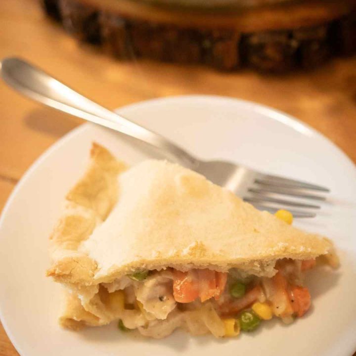 close up of sourdough chicken pot pie on a white plate with a fork