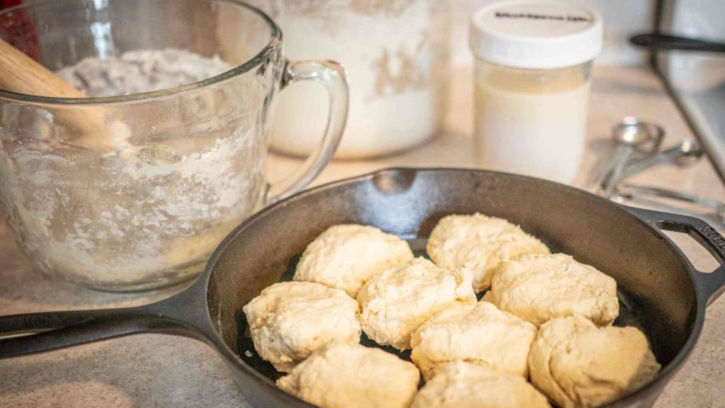 unbaked sourdough biscuits with ingredients and mixing bowl in the background