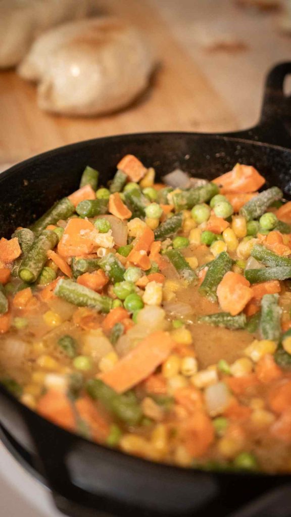 mixed vegetables cooking in a cast iron pan