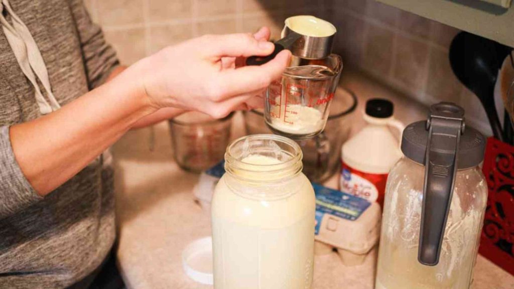 hand scooping cream off of a fresh jar of raw milk