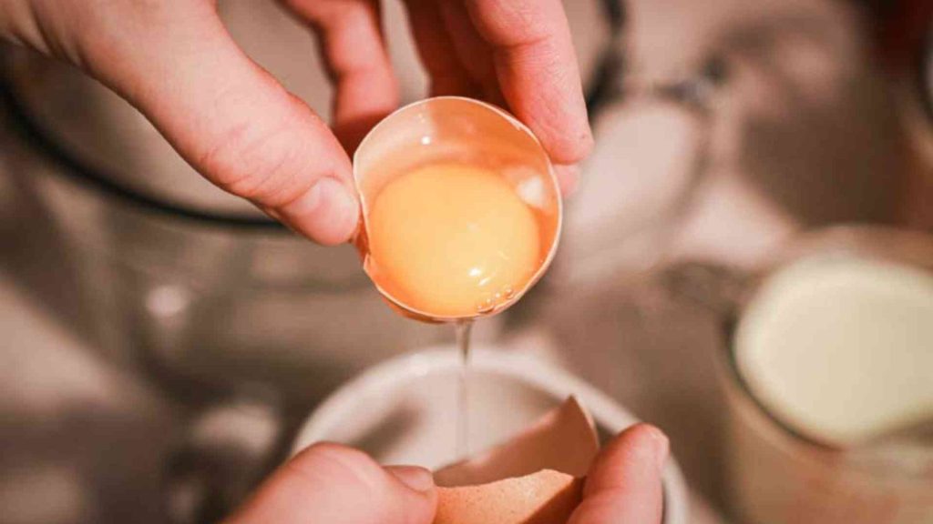 hands shown separating egg yolks from egg whites