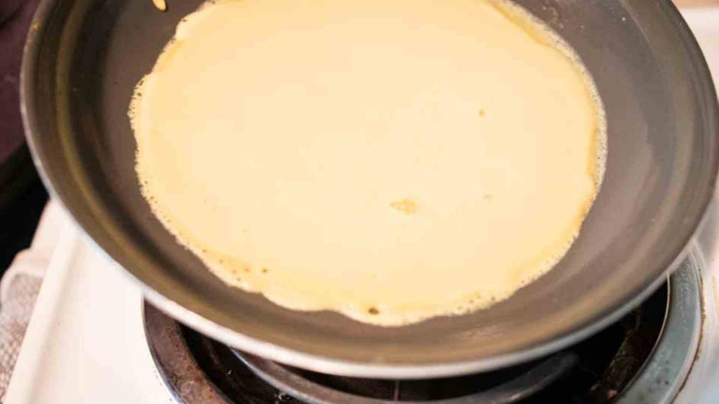 close up of frying pan with sourdough crepe batter cooking