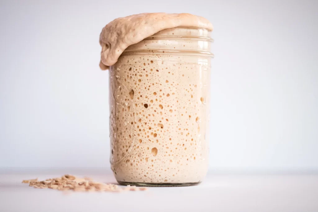 an active and bubbly sourdough starter overflowing in a jar