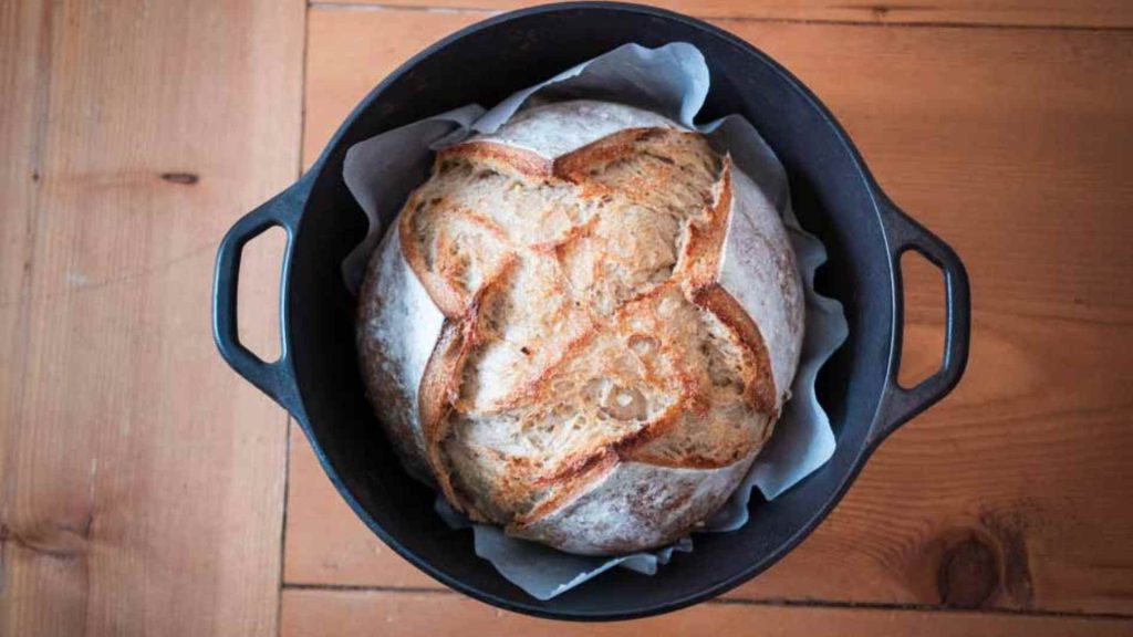 beautiful loaf of rosemary garlic sourdough bread in a dutch oven