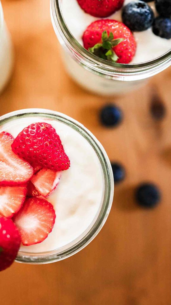 2 jars of raw milk instant pot yogurt with fresh strawberries and blueberries