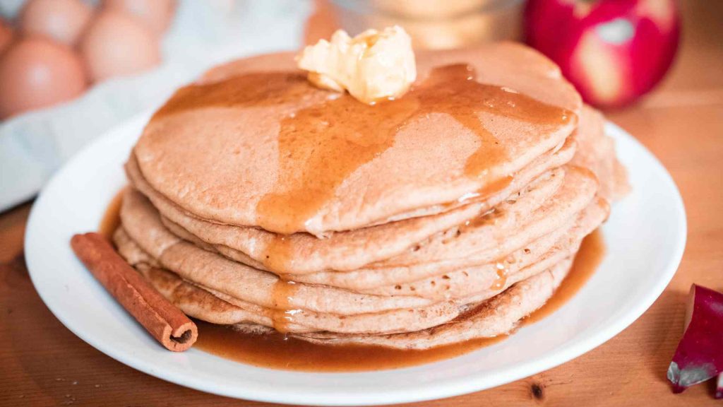stack of sourdough cinnamon pancakes with apple cider syrup and other ingredients next to it