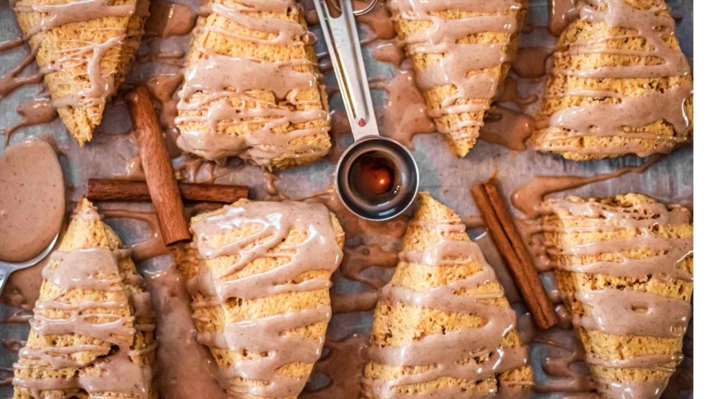 pumpkin sourdough scones on a baking sheet with maple spice glaze