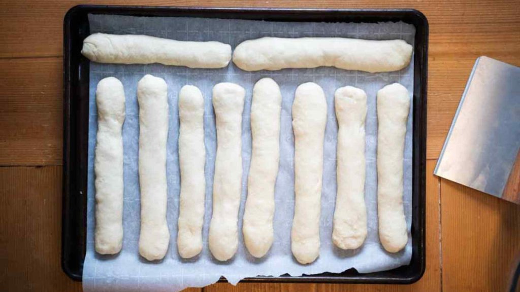 sourdough breadsticks arranged on a parchment lined baking sheet
