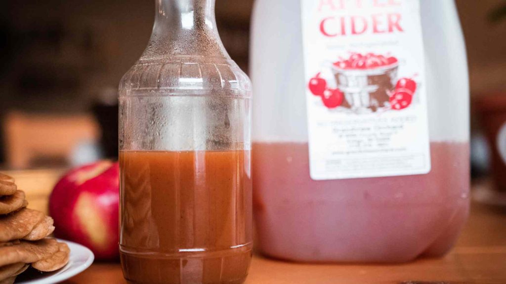 bottle of apple cider syrup with a jug of apple cider