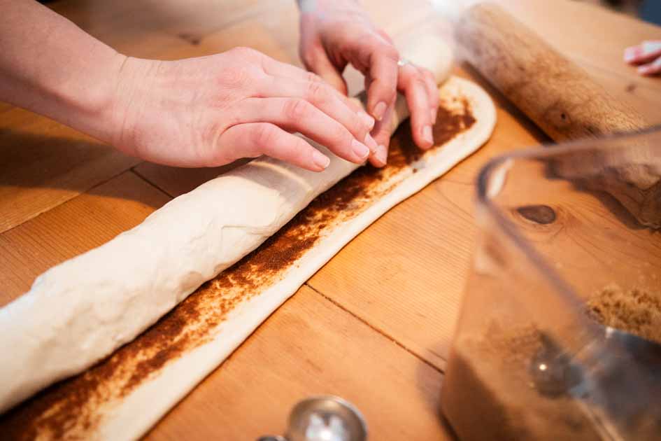 hands rolling sourdough cinnamon roll dough