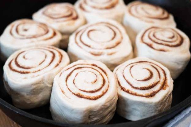 a cast iron skillet with unbaked cinnamon rolls in it