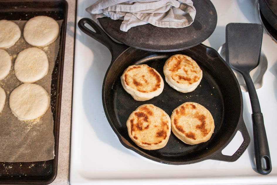 golden brown sourdough english muffins in a cast iron skillet