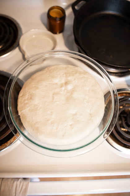 bubbly sourdough english muffin dough in a bowl on a stovetop