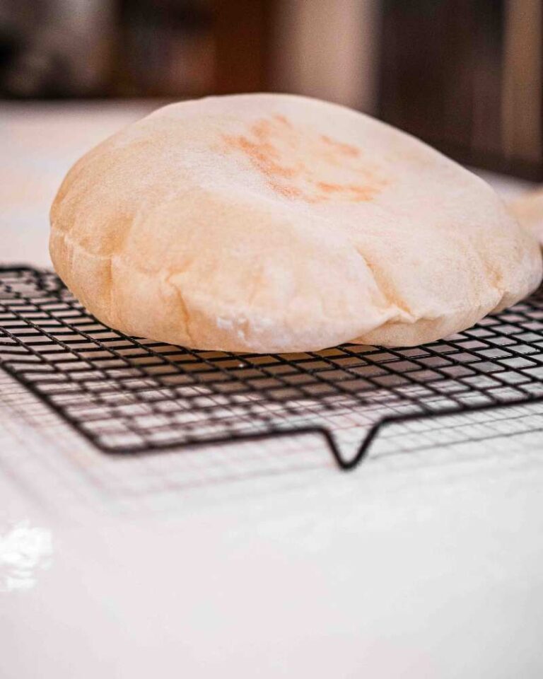 puffy sourdough pita bread on a cooling rack