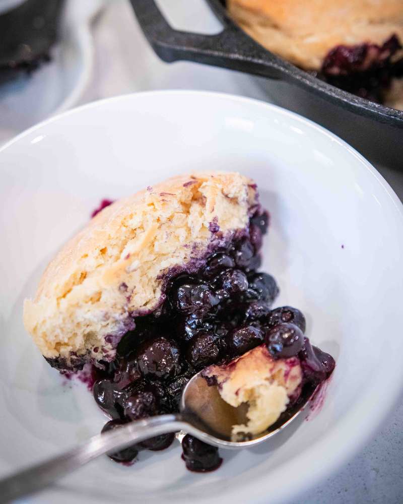 bowl of sourdough blueberry cobbler with a spoon