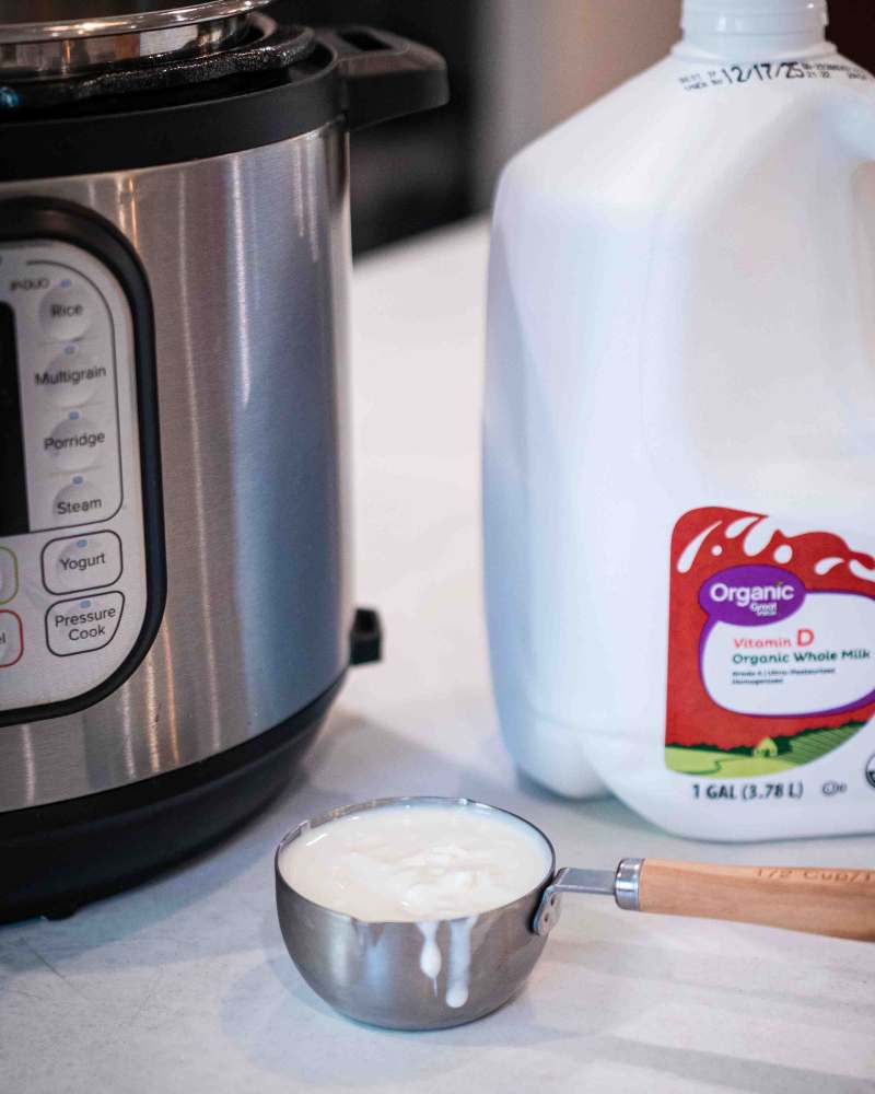 instant pot, whole milk and a measuring cup of yogurt